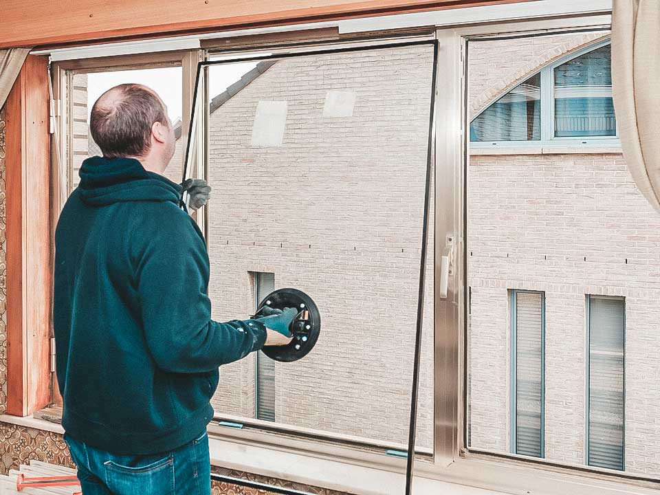 Vakman plaatst glas op maat met zuignappen tijdens de montage van een glazen deur